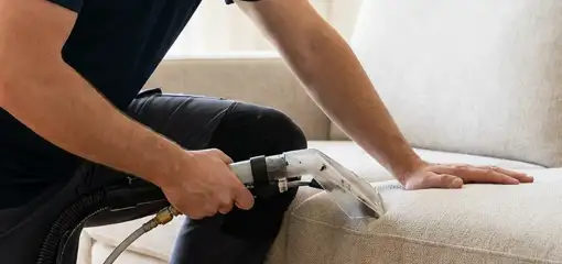 Professional upholstery cleaner deep-cleaning a fabric sofa with a handheld extraction tool, Anchorage, AK.